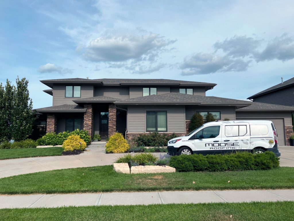 A home with a well-maintained roof and a roofing service van parked outside.