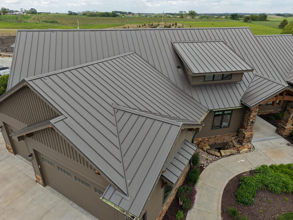 a residential home with a new standing seam metal roof by Moose Roofing. A roofing contractor in Omaha, Nebraska. The home sits on a open field landscape.