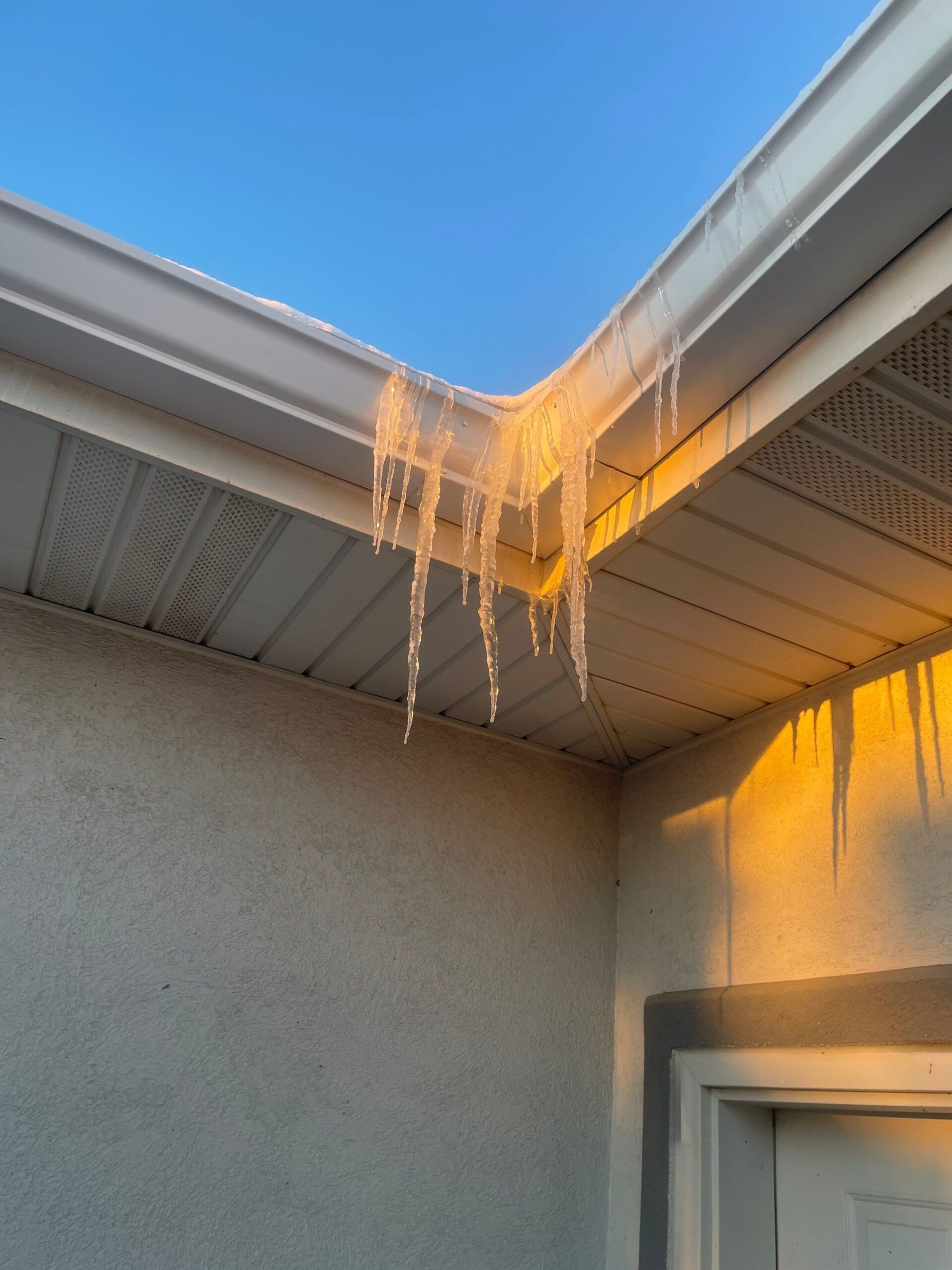 Ice dam forming along the edge of a residential roof in winter