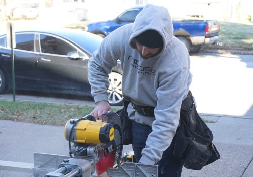 A worker uses a saw for roofing installation in an Omaha neighborhood.